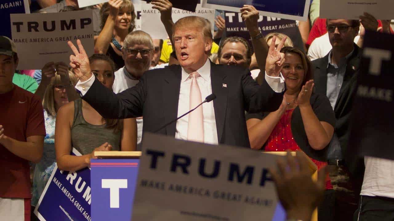 Donald Trump hablando en un mitin a una multitud de seguidores, transmitiendo temas que resuenan con los nacionalistas cristianos.